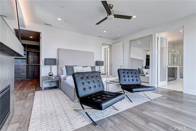 bedroom featuring hardwood / wood-style floors, ensuite bathroom, and ceiling fan