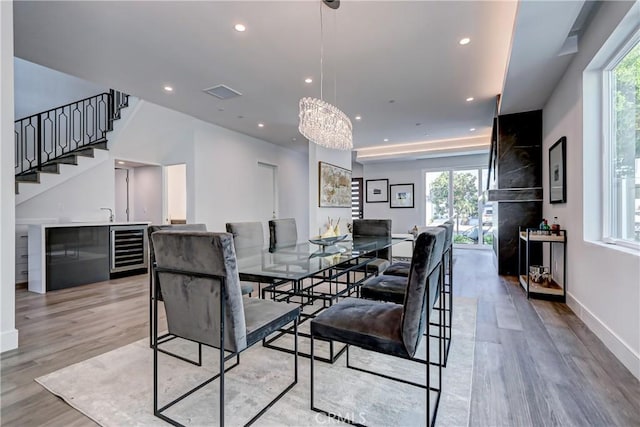 dining space with wine cooler, light hardwood / wood-style flooring, and a chandelier