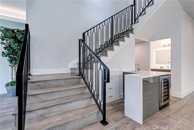 staircase with hardwood / wood-style floors, wine cooler, and sink