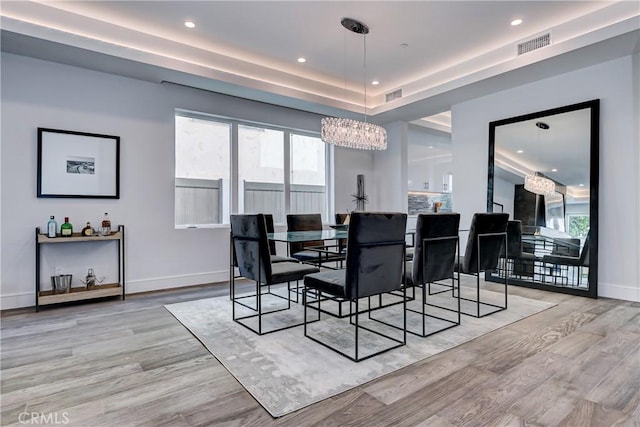 dining room with plenty of natural light, light wood-type flooring, and a notable chandelier