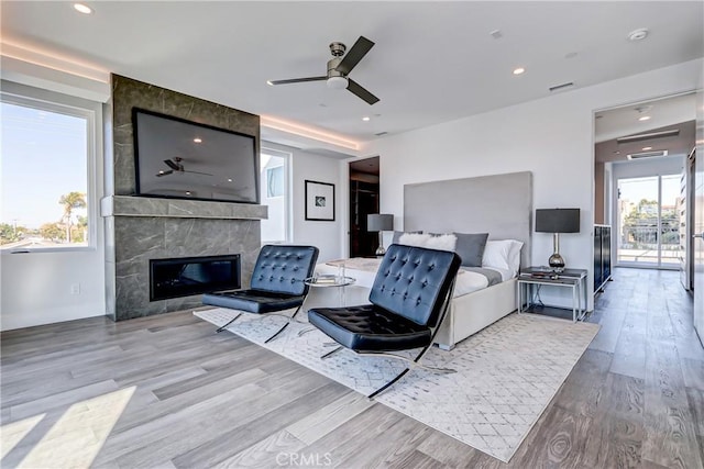 bedroom featuring a tiled fireplace and light hardwood / wood-style floors