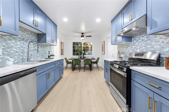 kitchen with blue cabinetry, ceiling fan, stainless steel appliances, decorative backsplash, and light wood-type flooring