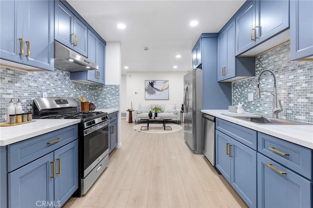 kitchen with blue cabinetry, sink, light hardwood / wood-style floors, decorative backsplash, and appliances with stainless steel finishes