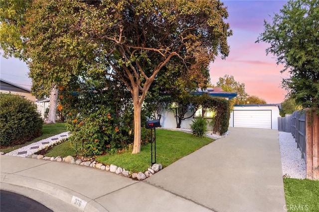 view of property hidden behind natural elements featuring a lawn and a garage