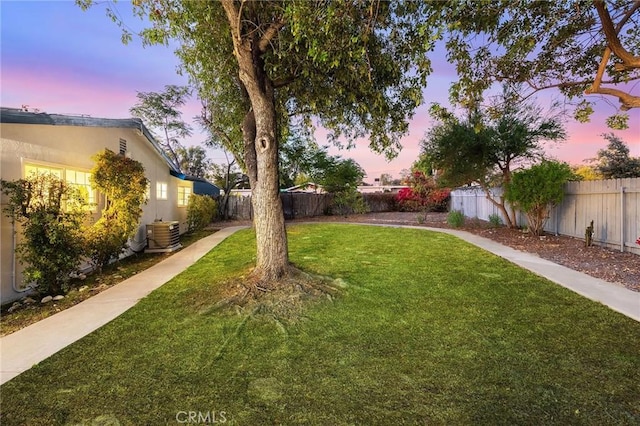 yard at dusk featuring central AC unit