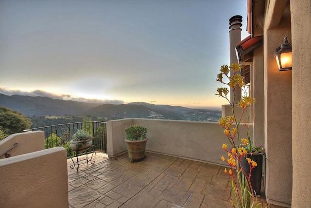 balcony at dusk featuring a mountain view