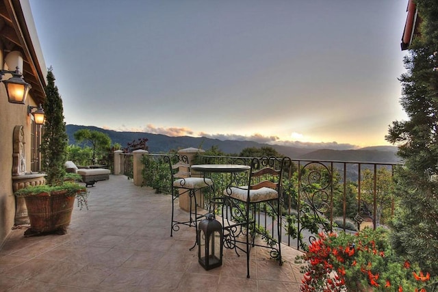 patio terrace at dusk featuring a mountain view and a balcony