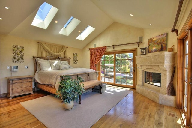 bedroom featuring a high end fireplace, access to exterior, high vaulted ceiling, and light hardwood / wood-style flooring