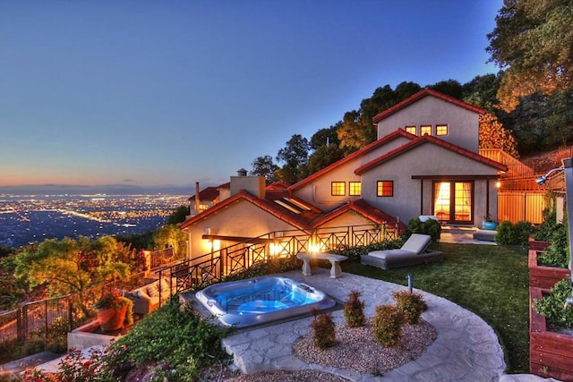 back house at dusk featuring an outdoor hot tub