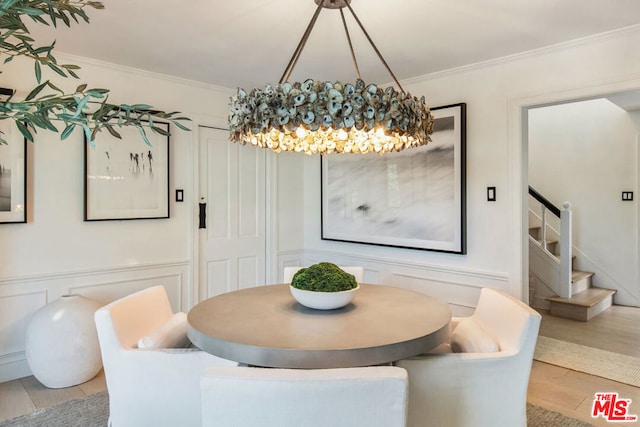 dining space with crown molding, an inviting chandelier, and light wood-type flooring