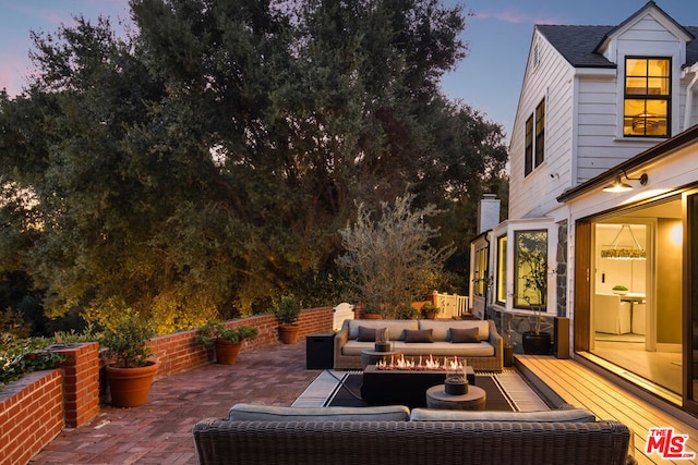 patio terrace at dusk with outdoor lounge area and a deck