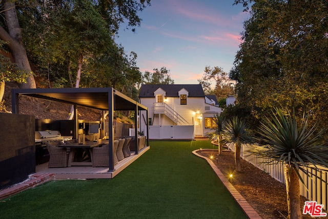 yard at dusk with outdoor lounge area and exterior kitchen