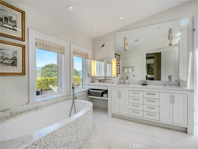 bathroom featuring tiled tub, vanity, and lofted ceiling