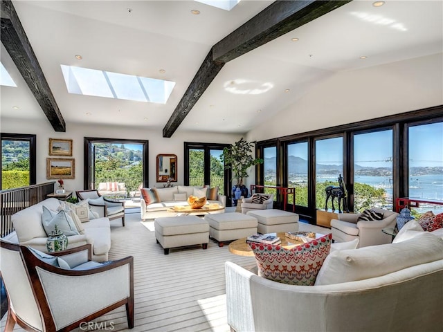 living room with french doors, light hardwood / wood-style floors, a water view, and vaulted ceiling with skylight