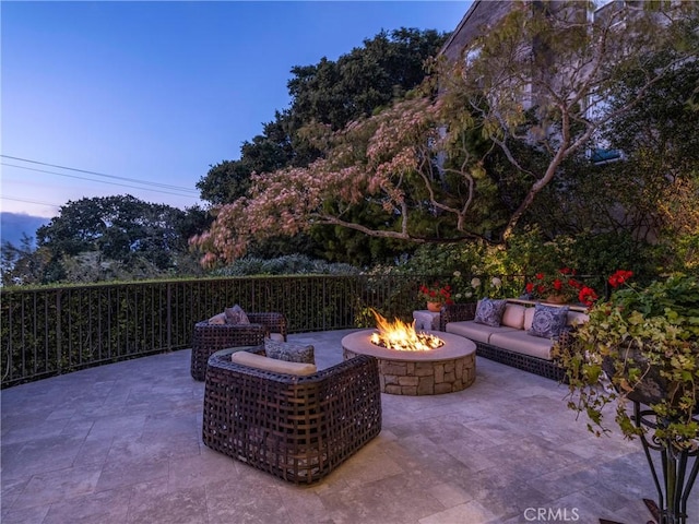 patio terrace at dusk with an outdoor living space with a fire pit