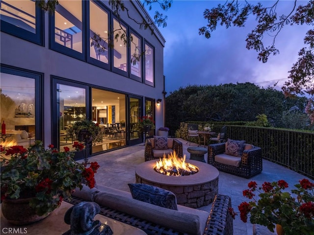 patio terrace at dusk with an outdoor living space with a fire pit