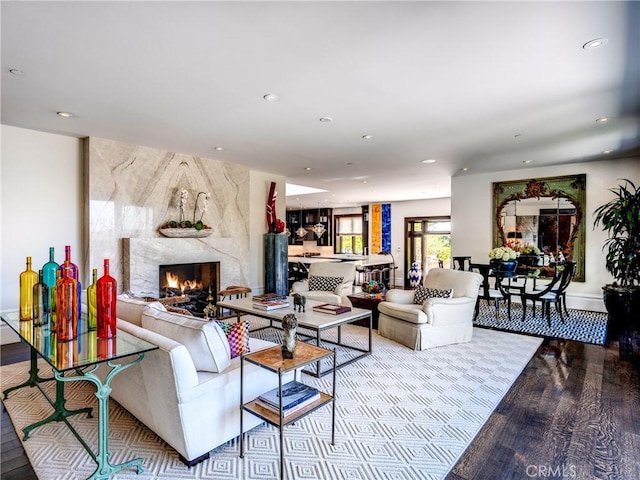 living room with a high end fireplace and light hardwood / wood-style flooring