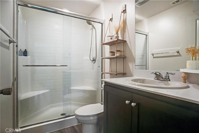 bathroom with hardwood / wood-style floors, vanity, toilet, and walk in shower