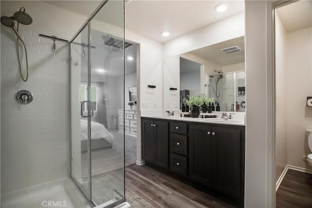 bathroom with hardwood / wood-style floors, vanity, toilet, and a shower with shower door