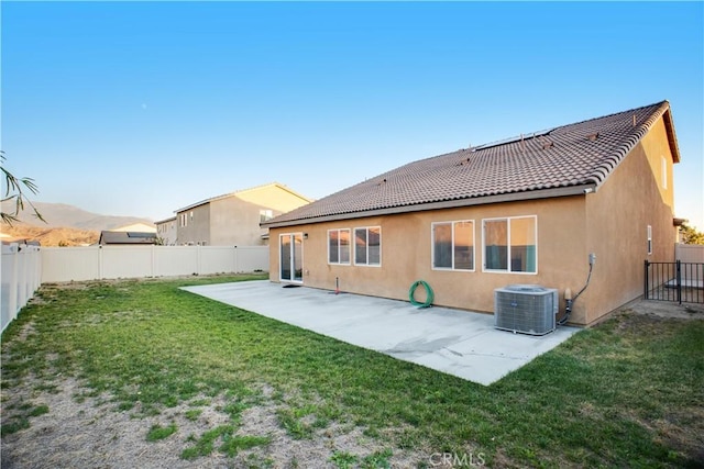 back of property featuring a lawn, a patio area, a mountain view, and central AC unit