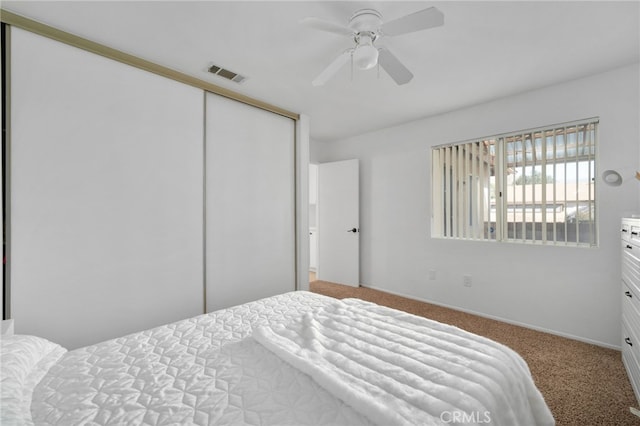 carpeted bedroom with ceiling fan and a closet