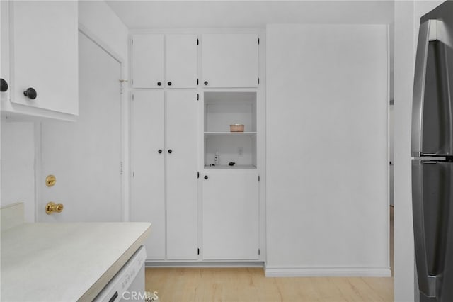 kitchen featuring stainless steel refrigerator, white cabinets, and light wood-type flooring