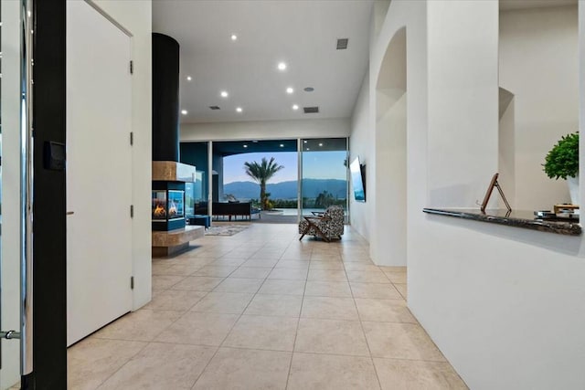 corridor with a mountain view, light tile patterned floors, and floor to ceiling windows