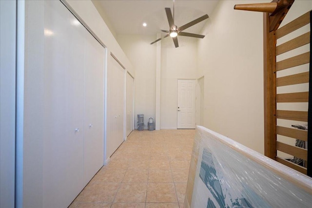 corridor featuring light tile patterned floors and high vaulted ceiling