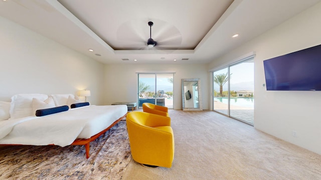 carpeted bedroom featuring access to outside, multiple windows, a raised ceiling, and ceiling fan