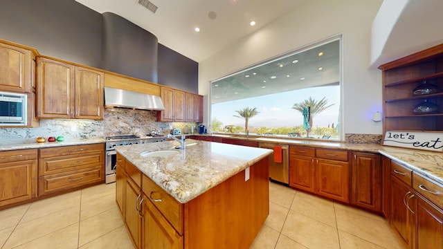 kitchen with sink, light stone counters, a kitchen island with sink, exhaust hood, and appliances with stainless steel finishes