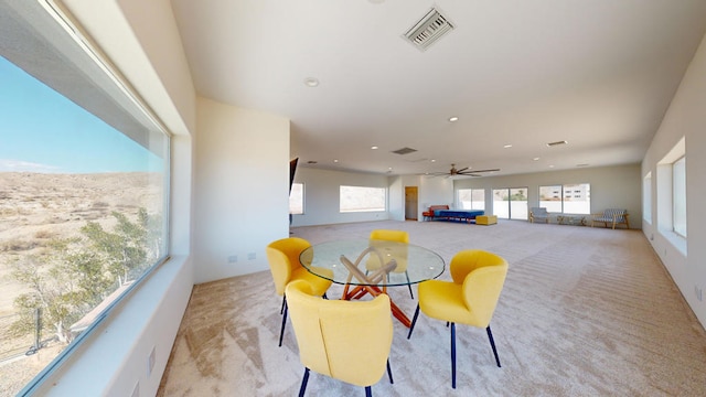 dining area with ceiling fan and light carpet