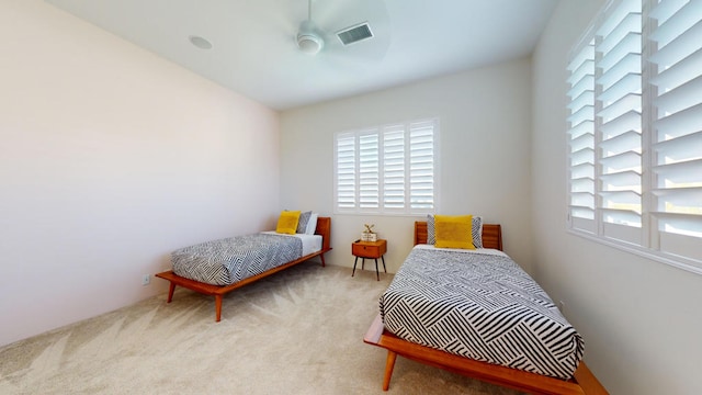 bedroom featuring ceiling fan, light carpet, and multiple windows