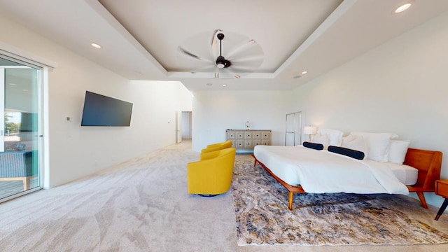 carpeted bedroom featuring ceiling fan, access to exterior, and a tray ceiling