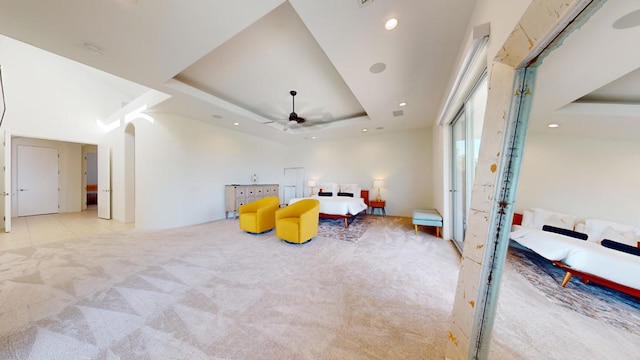 living area with light carpet, a tray ceiling, and ceiling fan