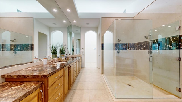 bathroom featuring tile patterned floors, vanity, a shower with door, and a skylight