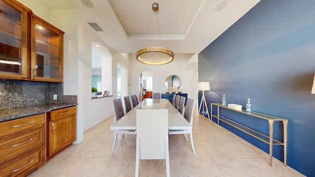 dining room with light tile patterned floors and a raised ceiling