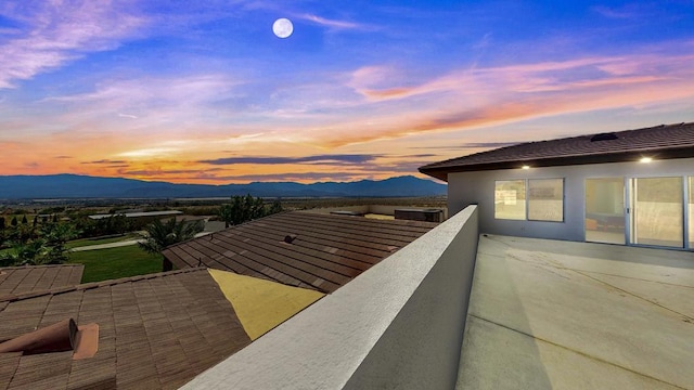 patio terrace at dusk with a mountain view and a balcony