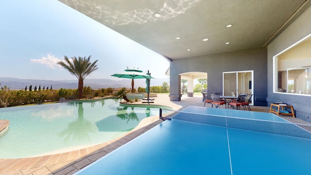 view of pool with a mountain view, a patio area, and a hot tub