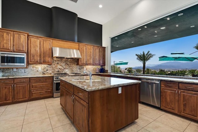 kitchen featuring a mountain view, ventilation hood, sink, an island with sink, and appliances with stainless steel finishes