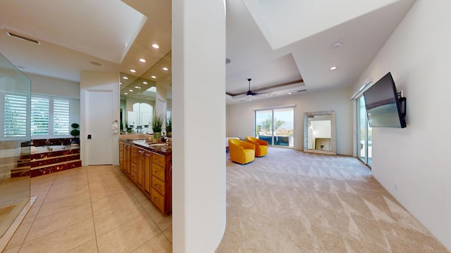 hall with sink, a raised ceiling, and light carpet