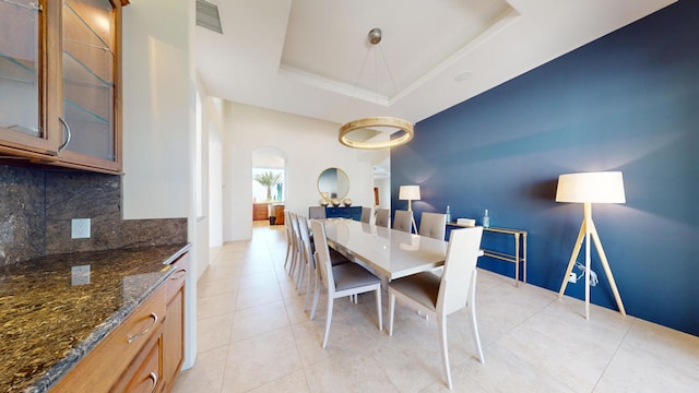 tiled dining space with a tray ceiling