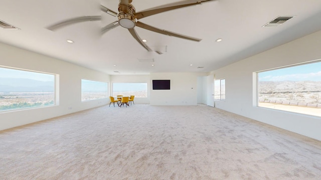 unfurnished living room featuring light carpet and ceiling fan