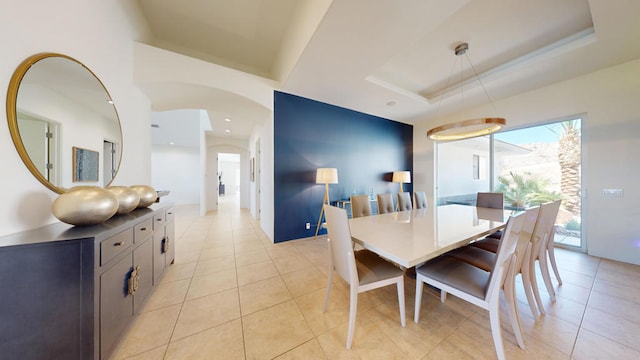 dining space featuring a tray ceiling and light tile patterned floors