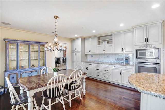 kitchen featuring light stone countertops, dark hardwood / wood-style flooring, pendant lighting, white cabinets, and appliances with stainless steel finishes