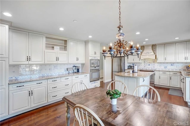 kitchen with white cabinets, custom exhaust hood, light stone countertops, and stainless steel appliances