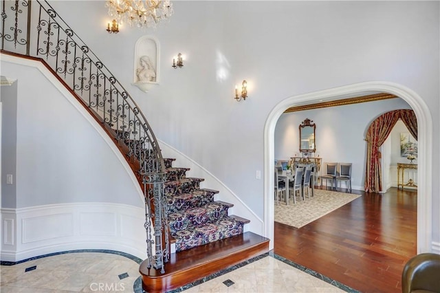 stairway featuring hardwood / wood-style floors, a towering ceiling, and a chandelier