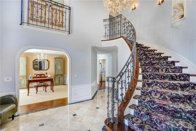 entrance foyer with hardwood / wood-style flooring, ornamental molding, a high ceiling, and a chandelier