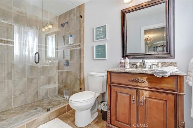 bathroom featuring tile patterned flooring, vanity, toilet, and a shower with door