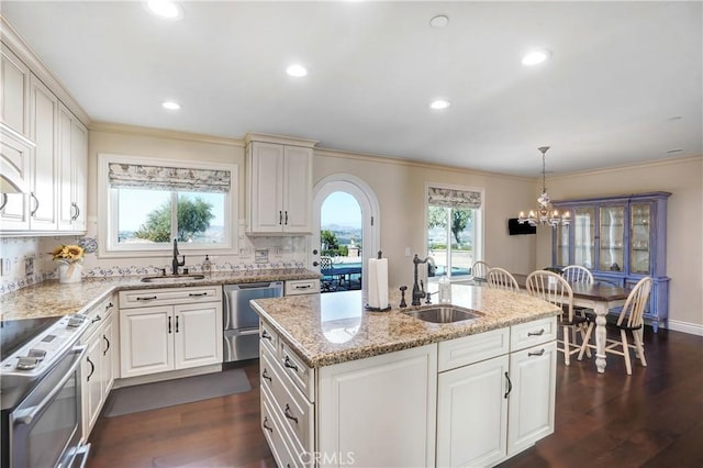 kitchen with pendant lighting, backsplash, sink, an island with sink, and appliances with stainless steel finishes