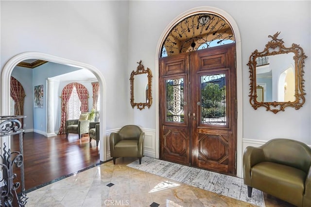 entryway with light hardwood / wood-style floors, a towering ceiling, and crown molding